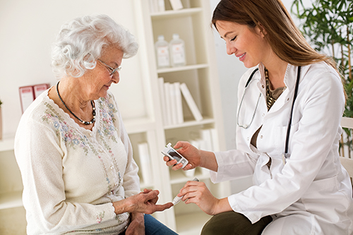 Young nurse checking an elderly woman's blood sugar