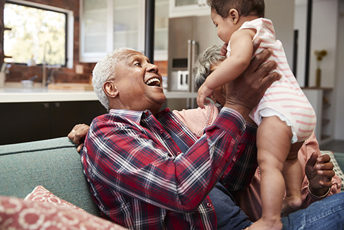 Grandfather holding his infant grandson up in the air smiling