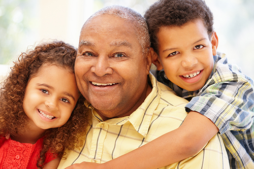 Grandfather in yellow shirt with his two young grandchildren